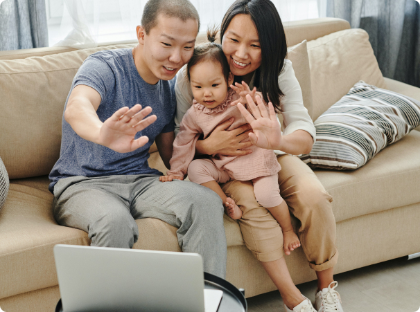 Parents and toddler waving towards a laptop